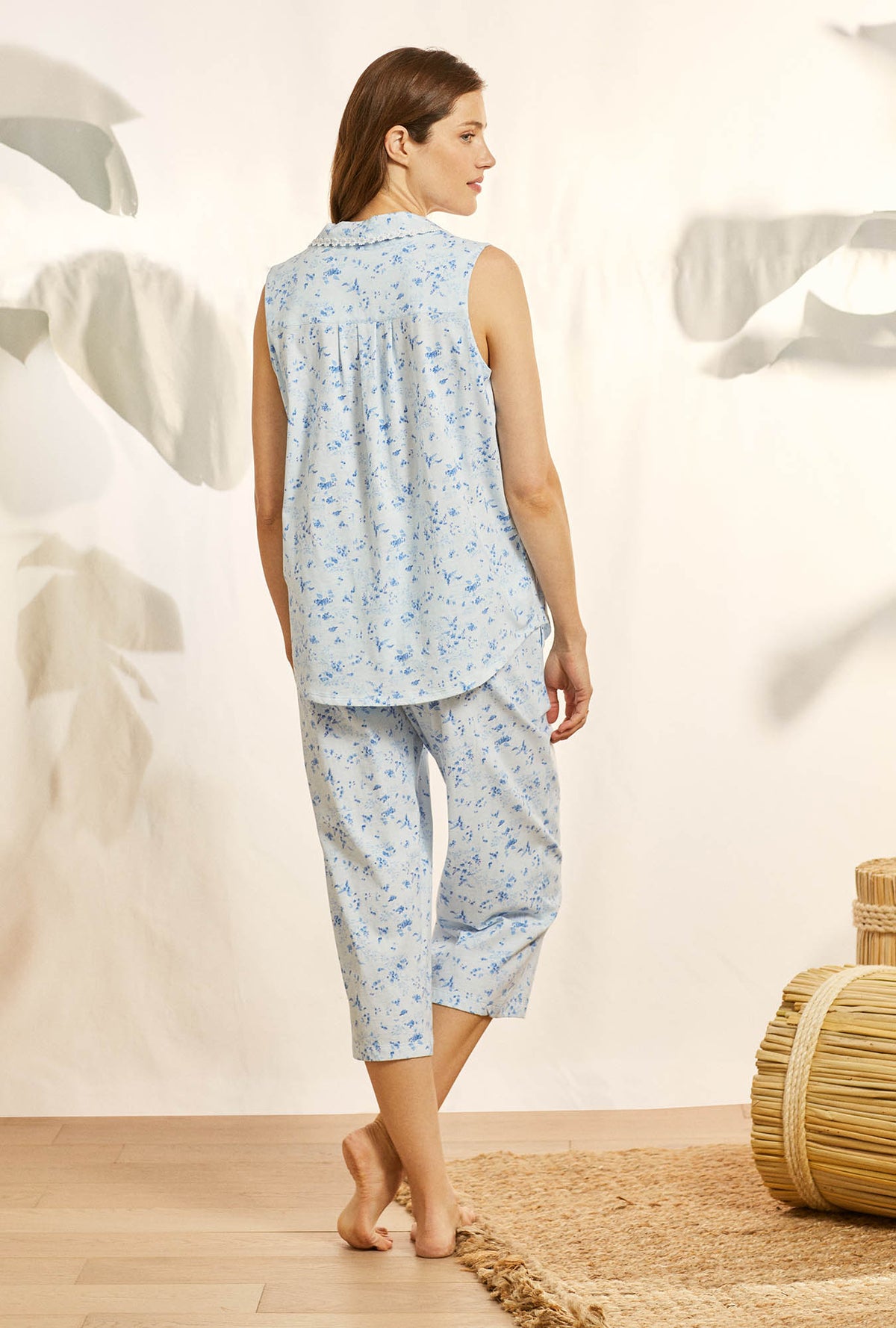 A lady wearing blue sleeveless cotton knit capri pajama with blue fields print.