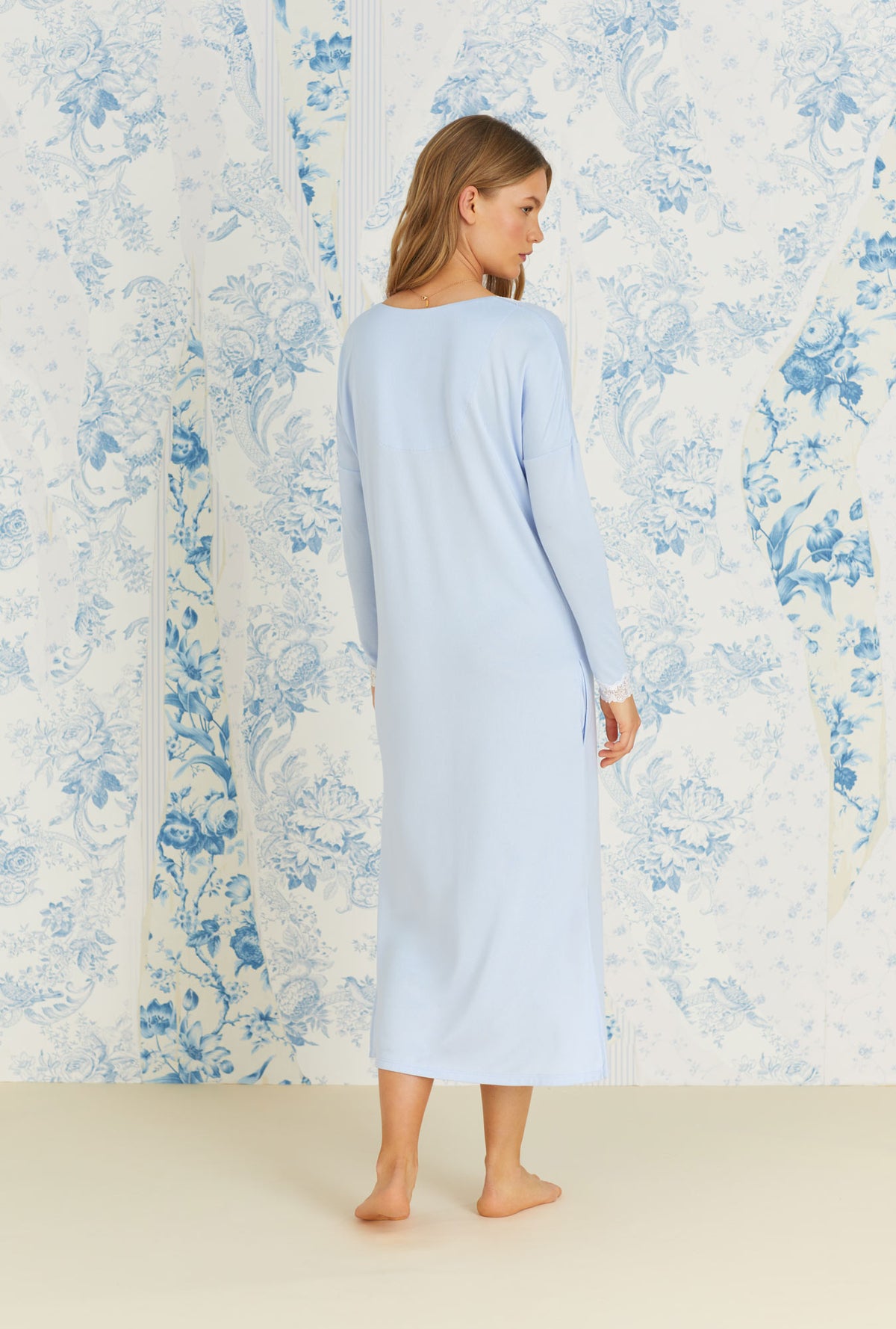 A lady wearing long sleeve blue cozy sweater knit long lounger nightgown.