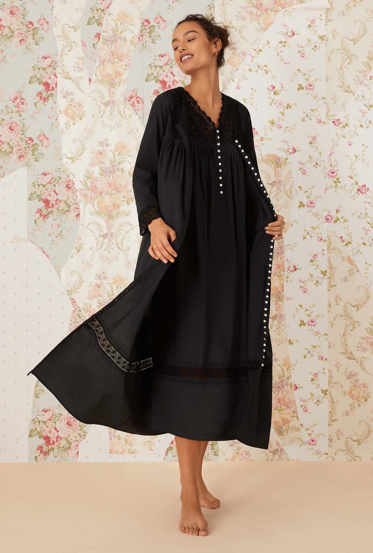 A lady wearing black long sleeve portofino ballet button front robe.