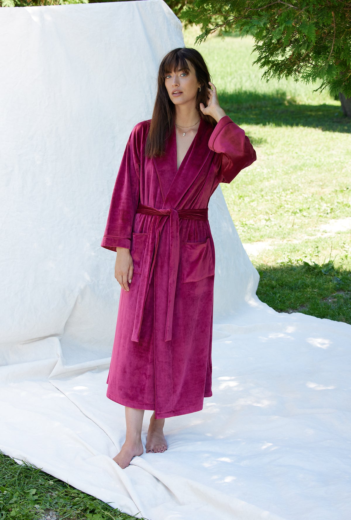 A lady wearing a crimson long sleeve lux velour long wrap robe.