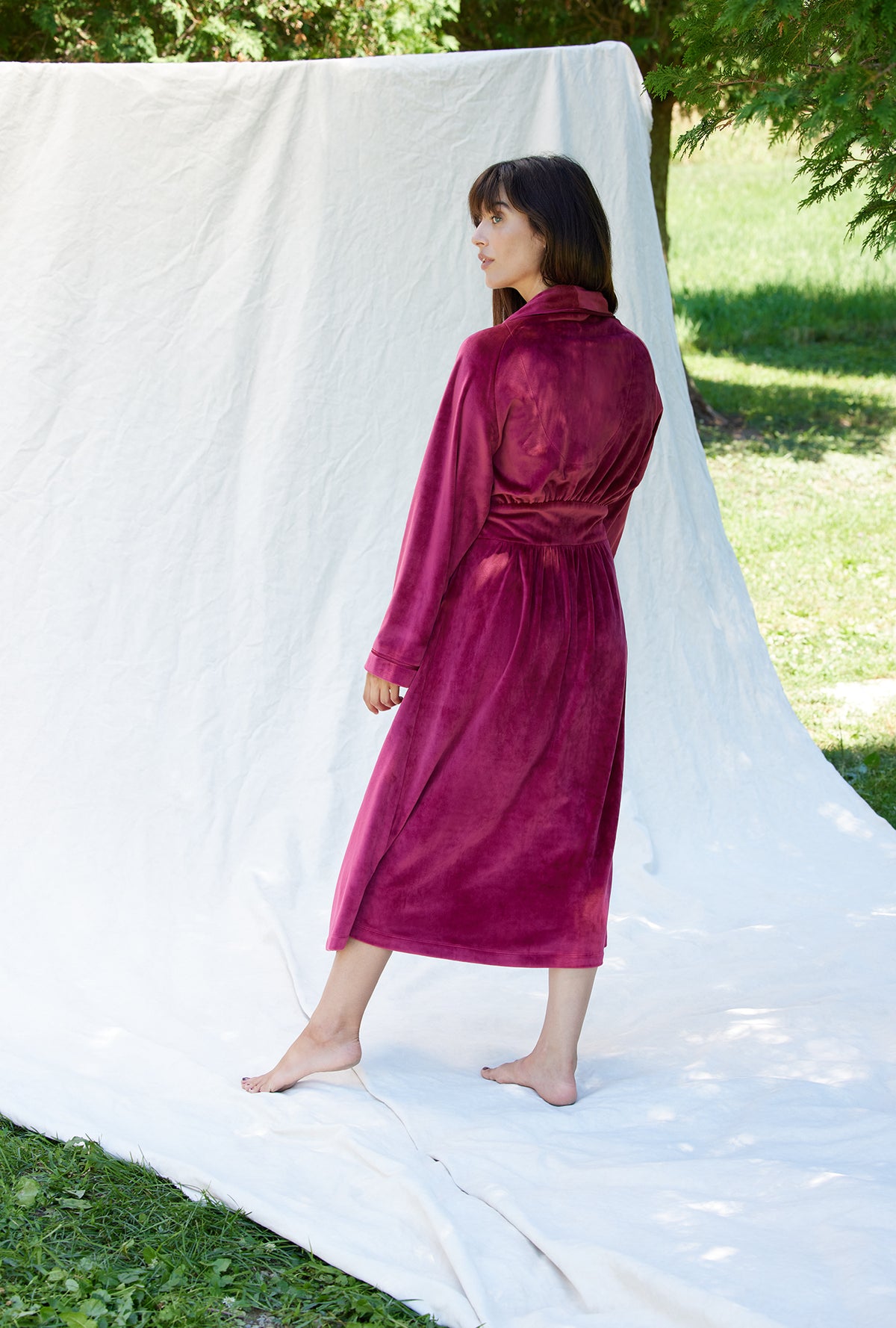 A lady wearing a crimson long sleeve lux velour long wrap robe.