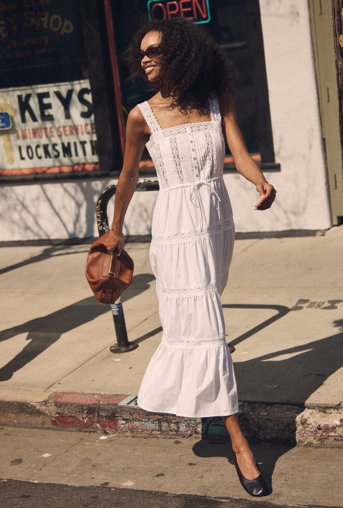 A lady wearing The "Elise" Soft White Cotton Maxi Dress walking looking side