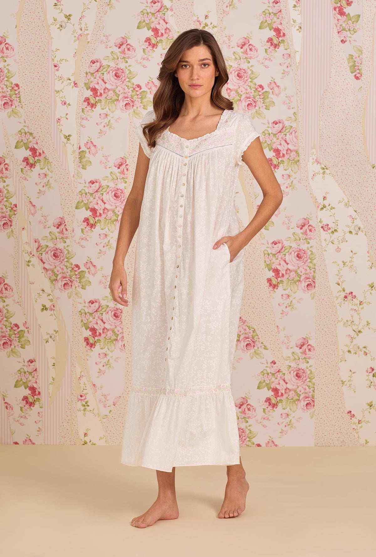 A Lady Wearing Shadow Floral Cotton Lawn Button Front Robe facing front in a side angle pose, with placing one hand inside her pocket