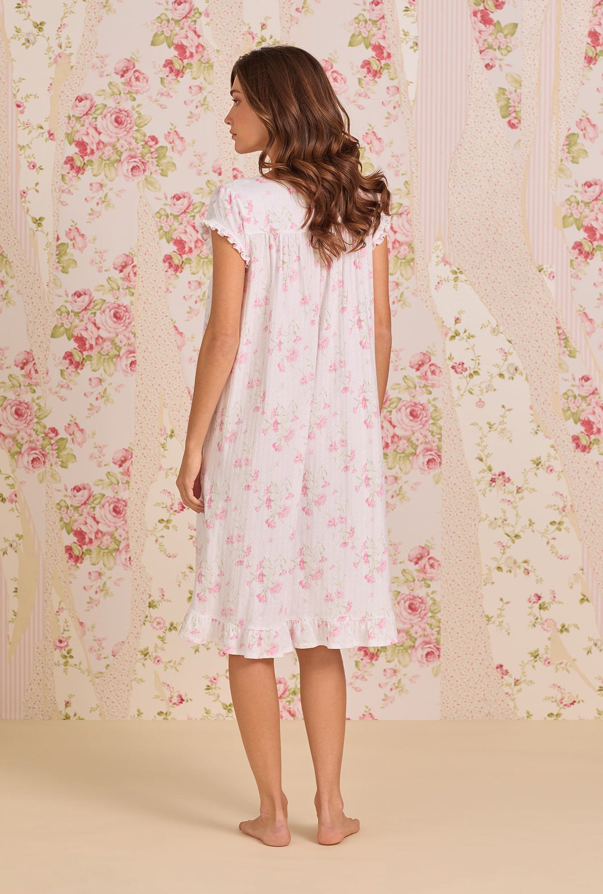 A Lady Wearing Blush Carnation Cotton Pointelle Waltz Nightgown facing back view of the dress while looking to the side