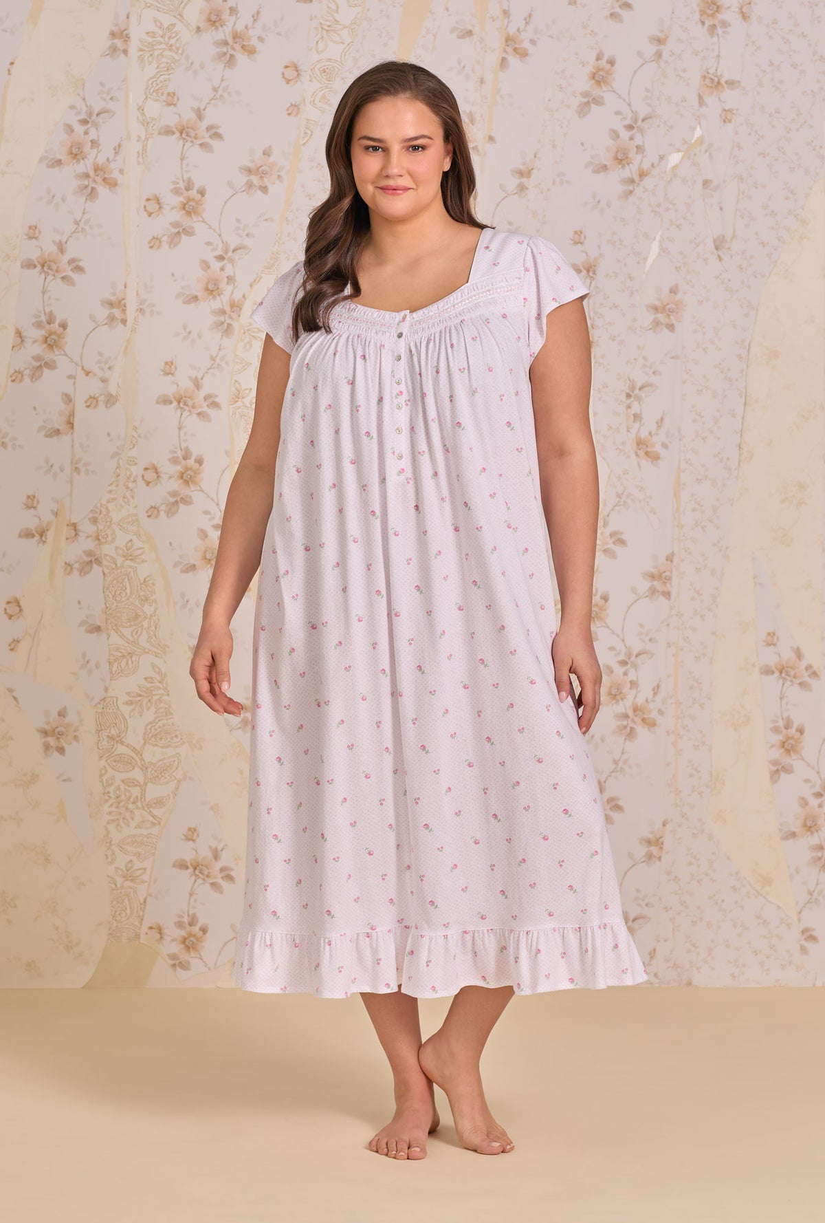 A Lady Wearing Plus Size Petite Dot Cotton Knit Cap Sleeve Ballet Nightgown facing front in a full standing pose against the floral background