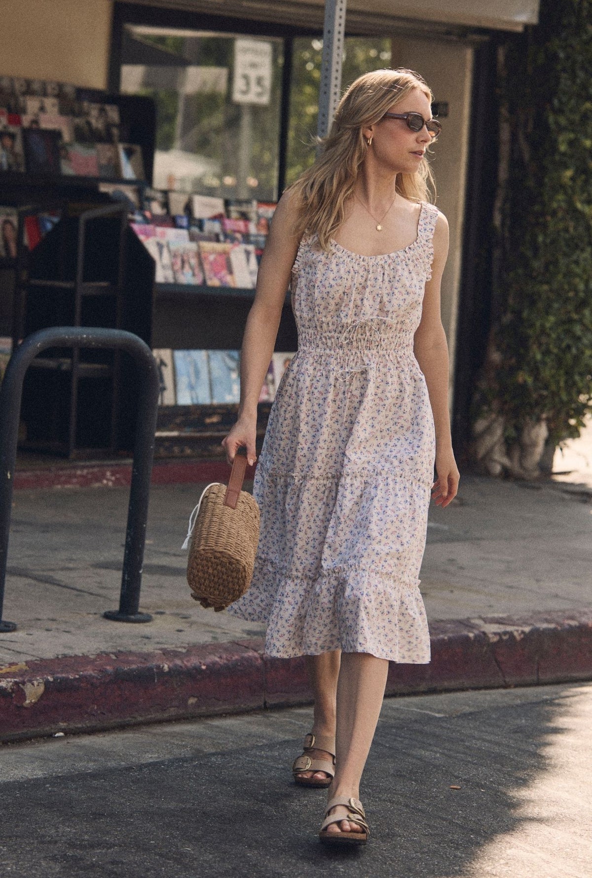 A lady wearing The "Nora" Buttercup Floral Cotton Midi Dress walking 