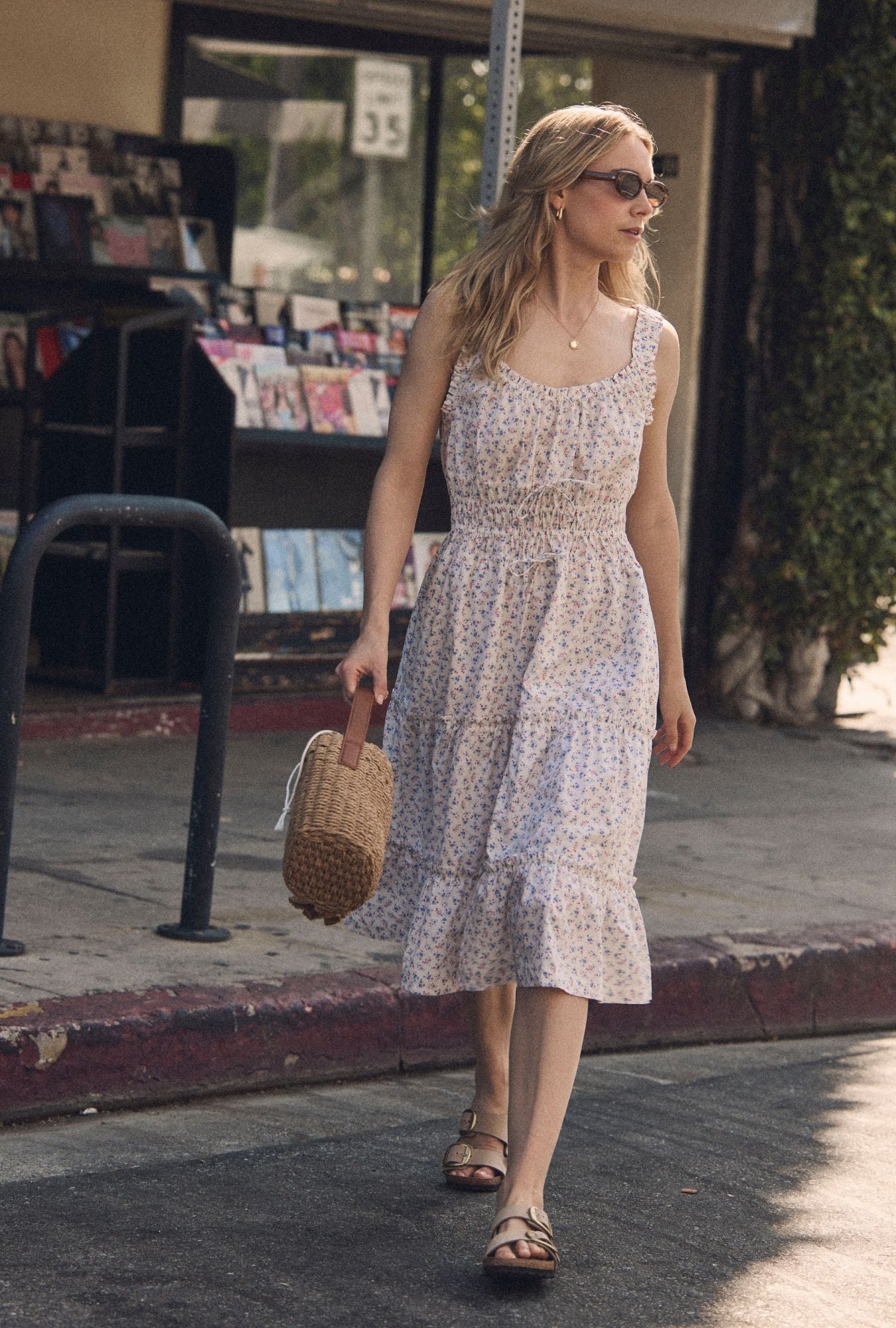 A lady wearing The "Nora" Buttercup Floral Cotton Midi Dress walking 