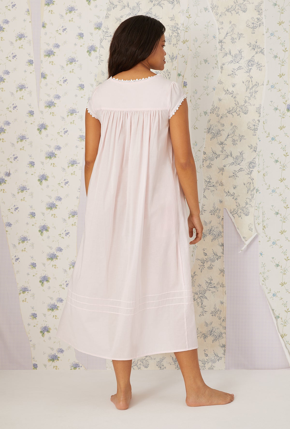 A lady wearing plus size Heirloom Dream Cap Sleeve Nightgown in a back view pose in blush pink