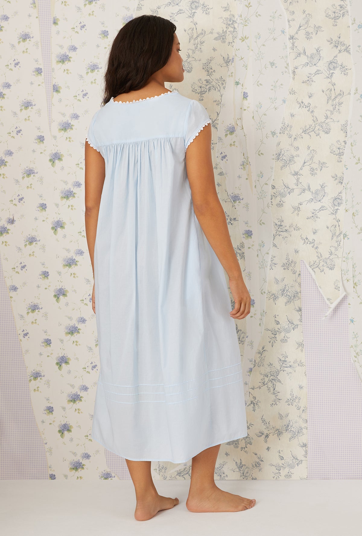 A lady wearing plus size Heirloom Dream Cap Sleeve Nightgown in light blue in a back view pose