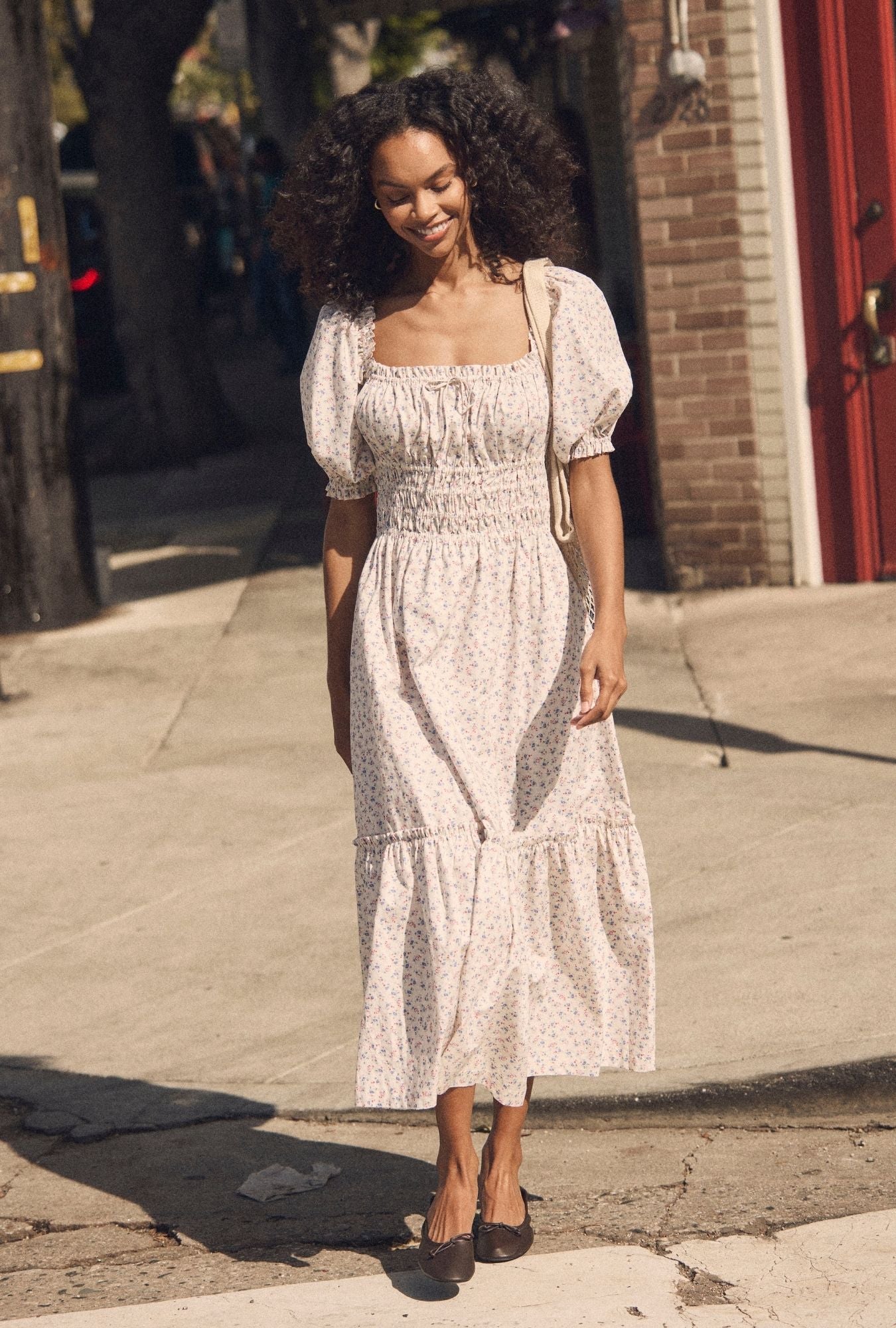 A lady wearing The "Marin" Buttercup Floral Cotton Maxi Dress walking looking down
