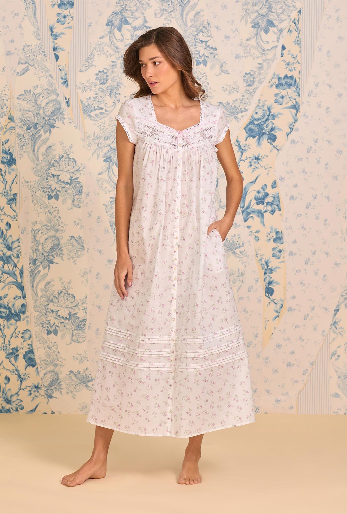 A Lady Wearing Petite Rose Cotton Lawn Button Front Robe facing front in a full standing pose with one hand in her pocket