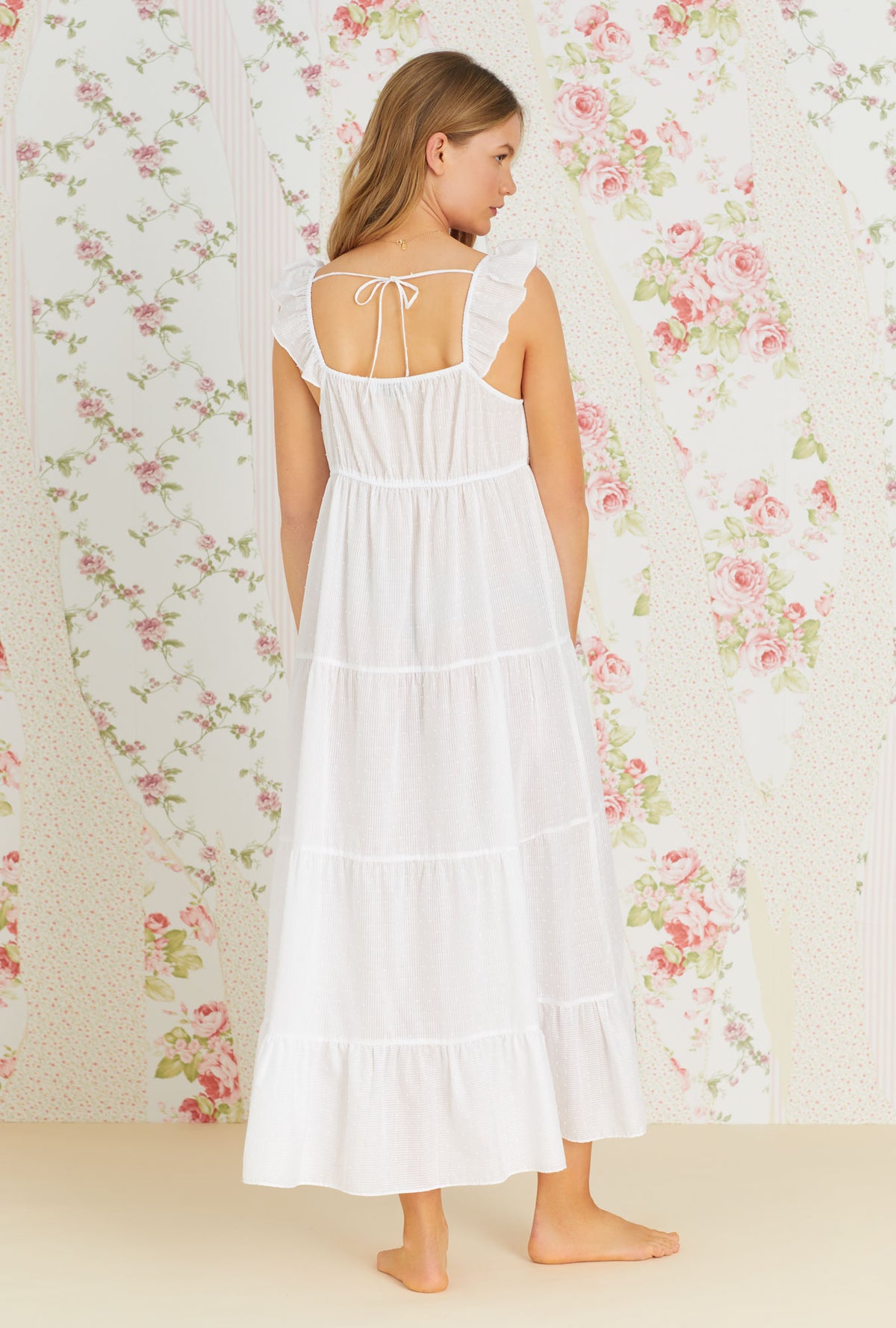 A lady wearing white sleeveless sheer stripe clip dot gown with sandy white jade pattern.