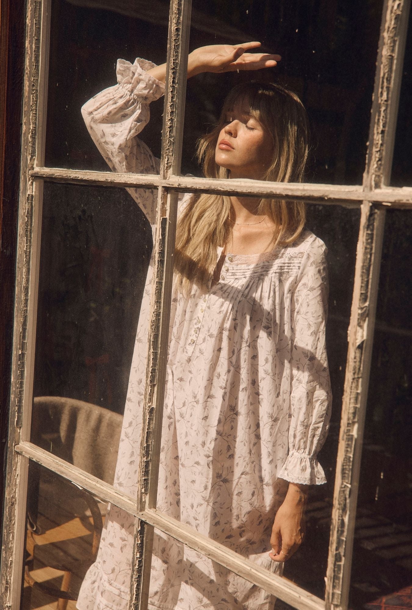 A lady wearing Silver Willow 100% Cotton Woven Lawn Long Sleeve Ballet Nightgown near a window