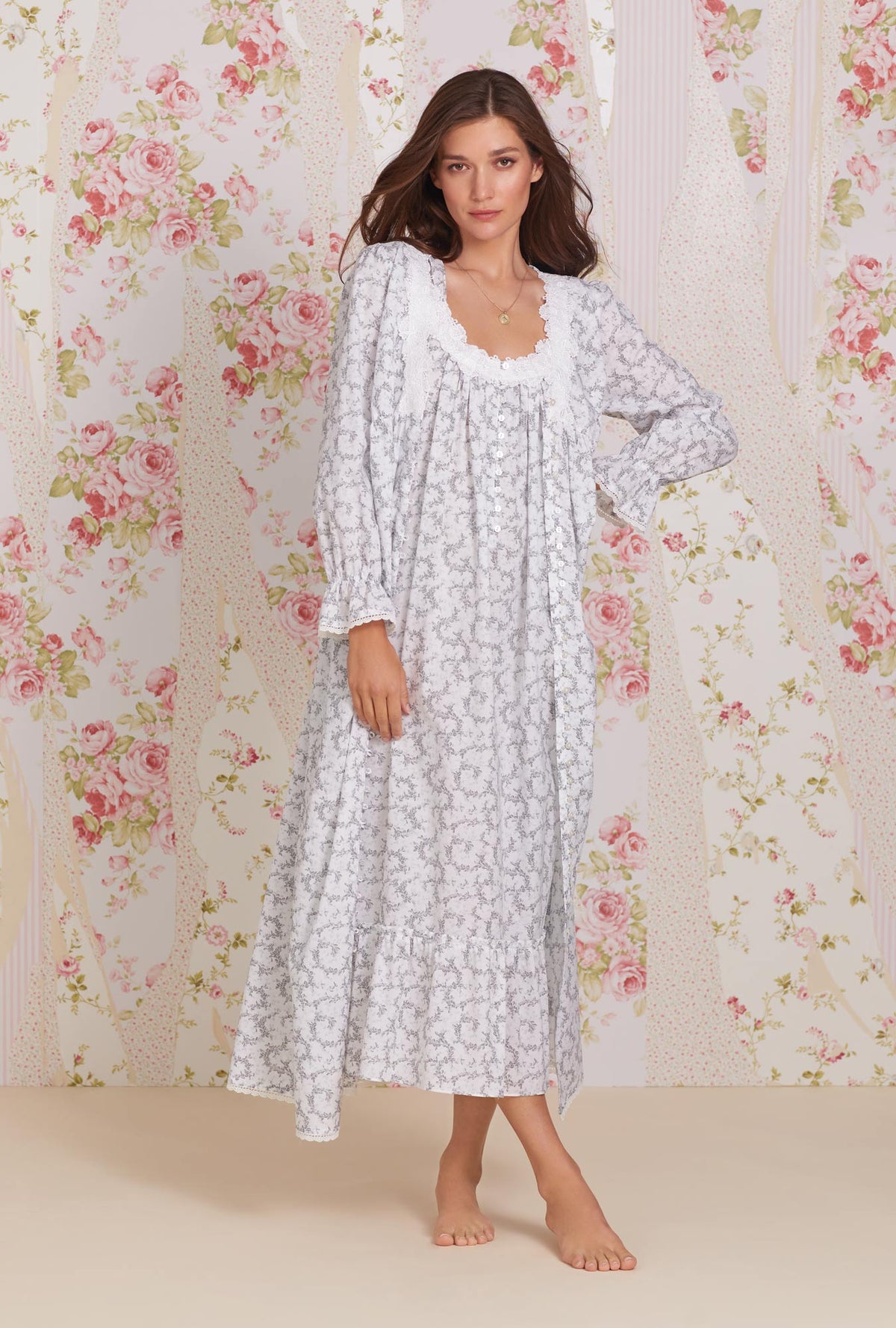 A lady wearing white long sleeve cotton button front robe with grey fleur print.