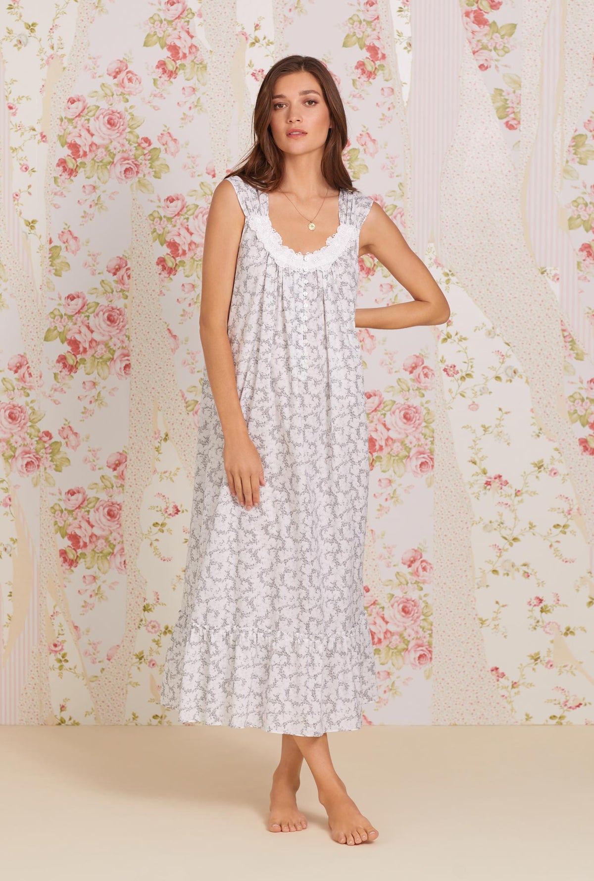 A lady wearing white sleeveless tabitha cotton nightgown with grey fleur print.