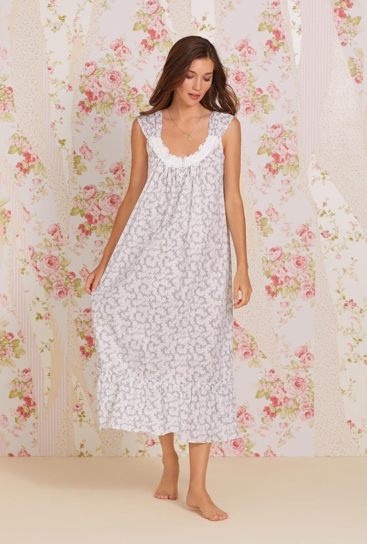 A lady wearing white sleeveless tabitha cotton nightgown with grey fleur print.
