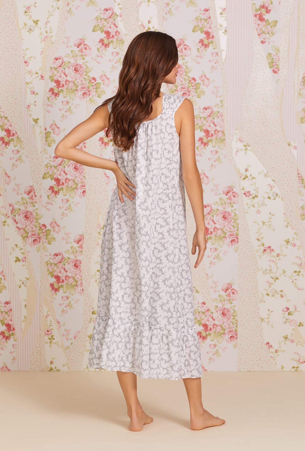 A lady wearing white sleeveless tabitha cotton nightgown with grey fleur print.
