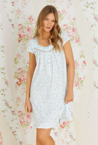 A lady wearing white cap sleeve cotton knit short nightgown with aqua scroll print.