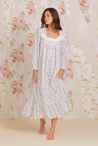 A lady wearing white long sleeve eileen cotton nightgown with grey fleur print.