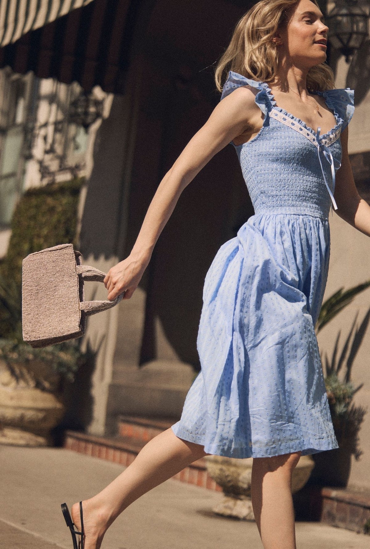 A lady wearing The "Ada" Bluebell Peri Cotton Swiss Dot Midi Dress side running side view