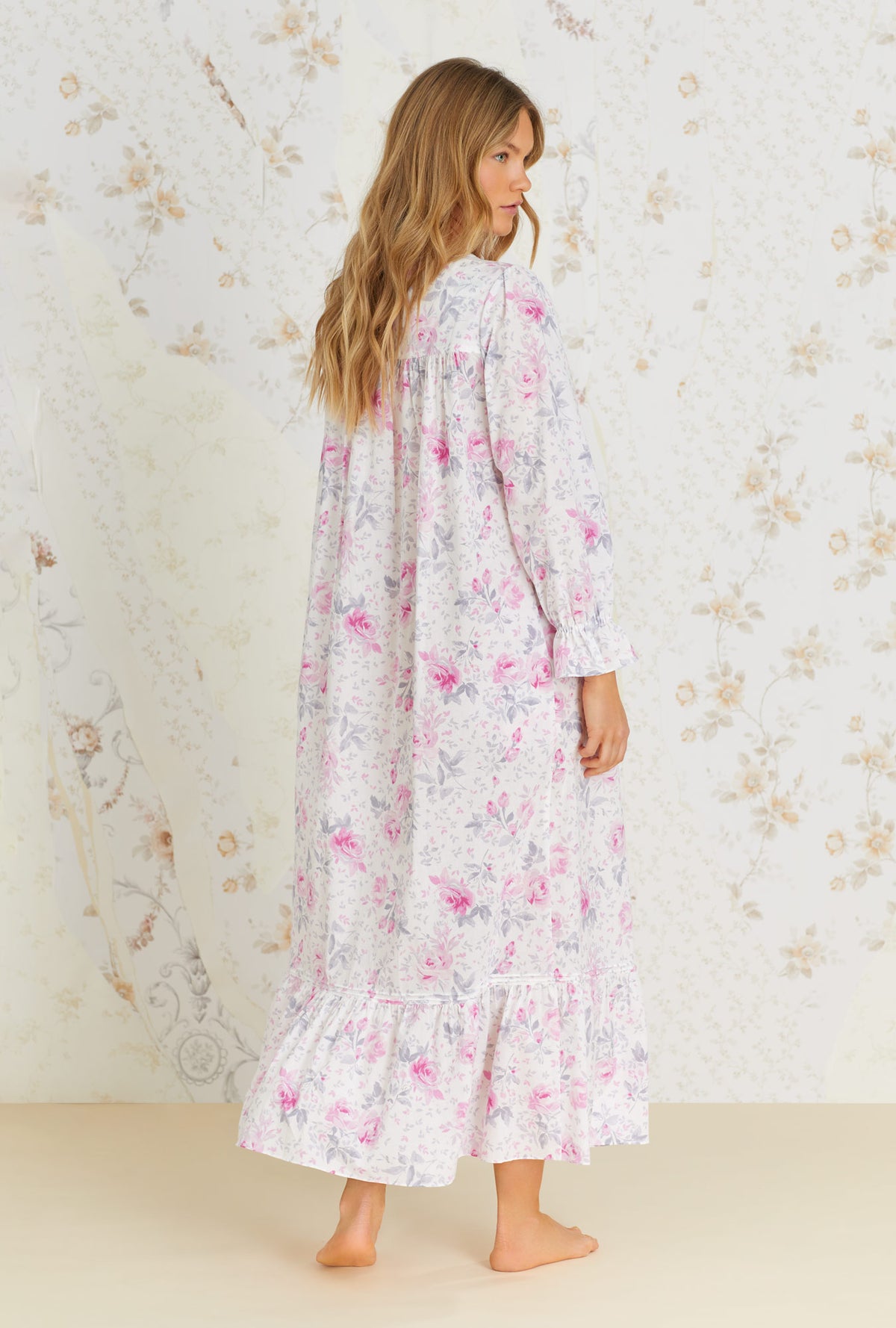 A lady wearing white long sleeve cotton button front robe with mendocino rose print.