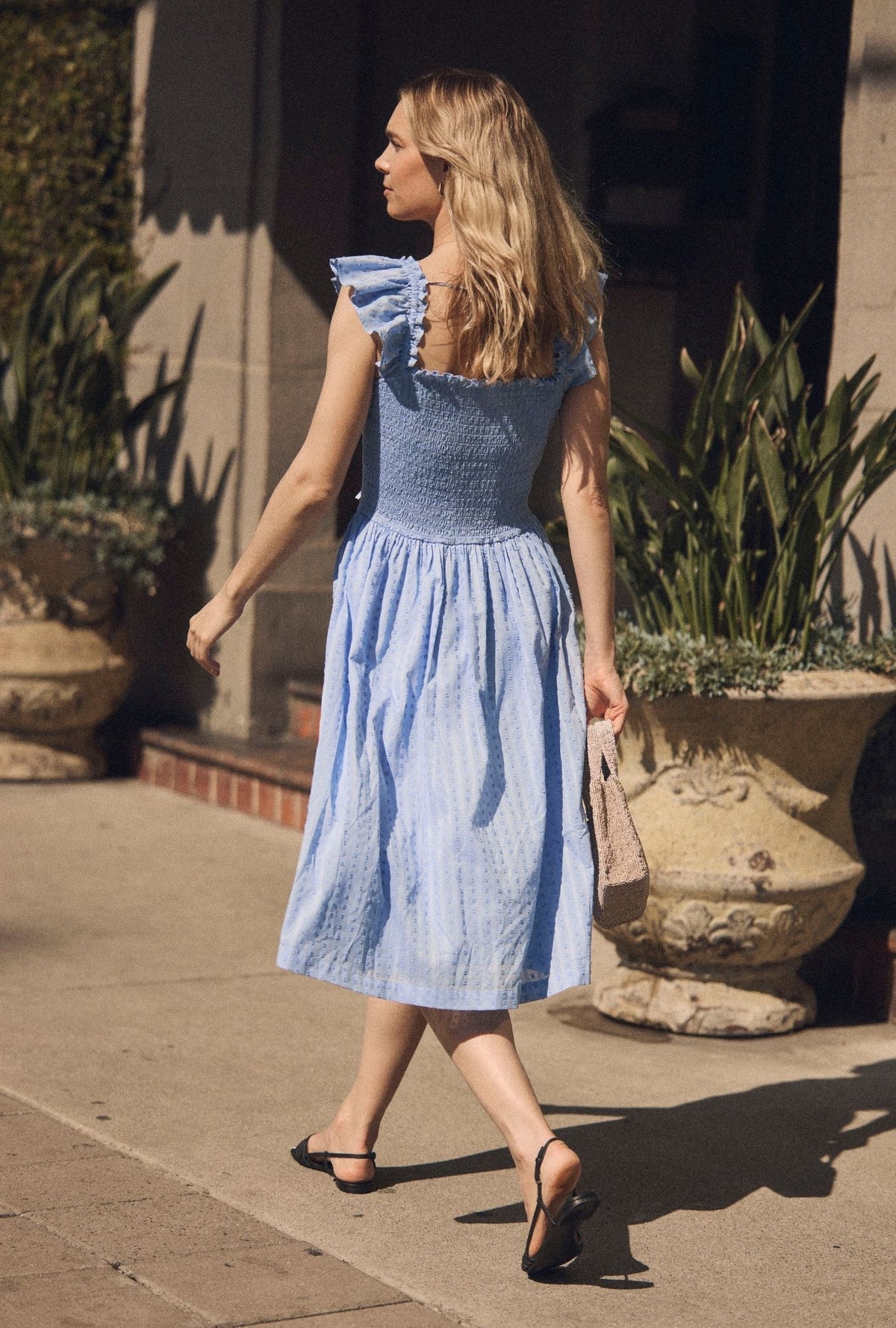 A lady wearing The "Ada" Bluebell Peri Cotton Swiss Dot Midi Dress looking side back view