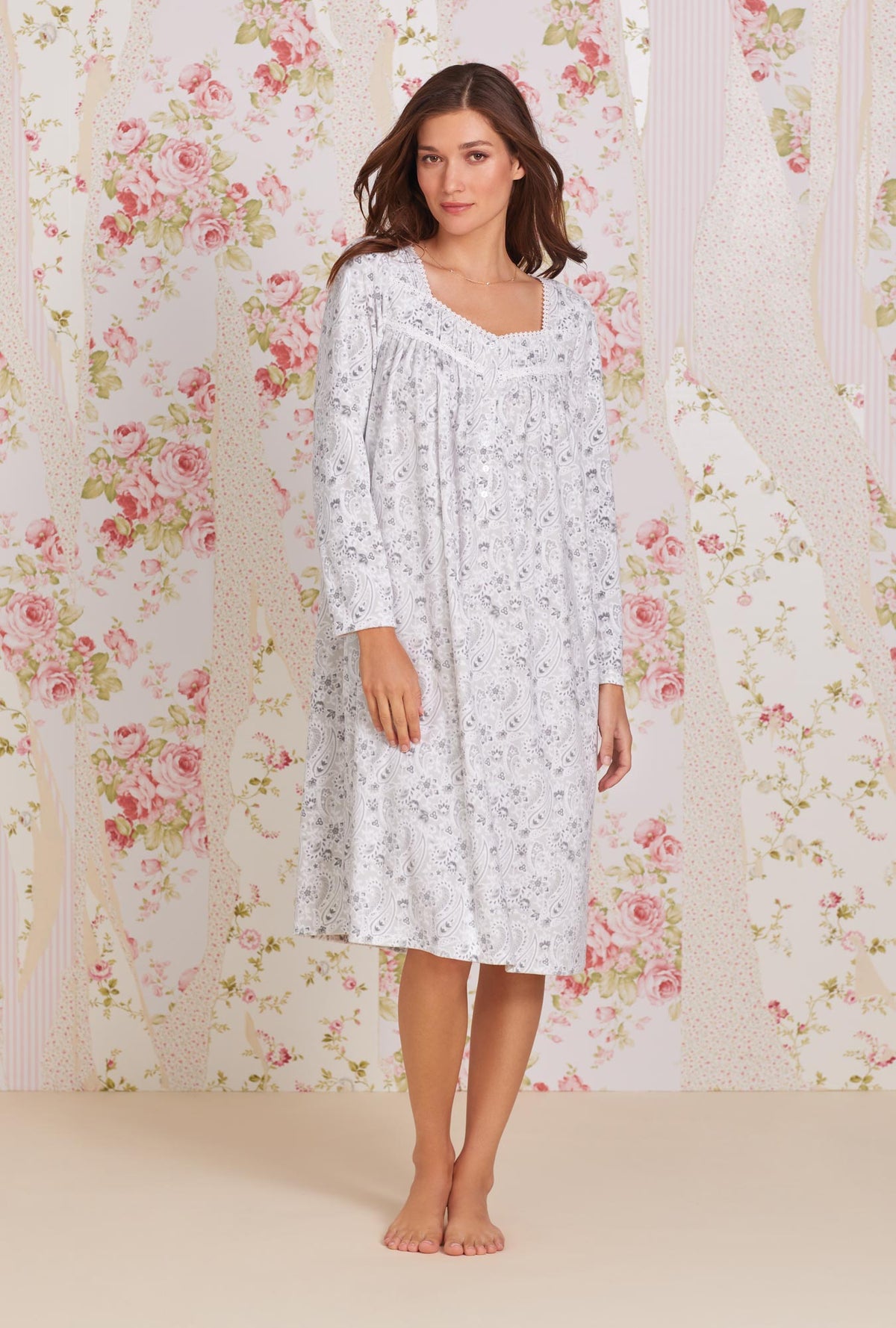 A lady wearing white long sleeve soft fleece waltz nightgown with grey paisley print.