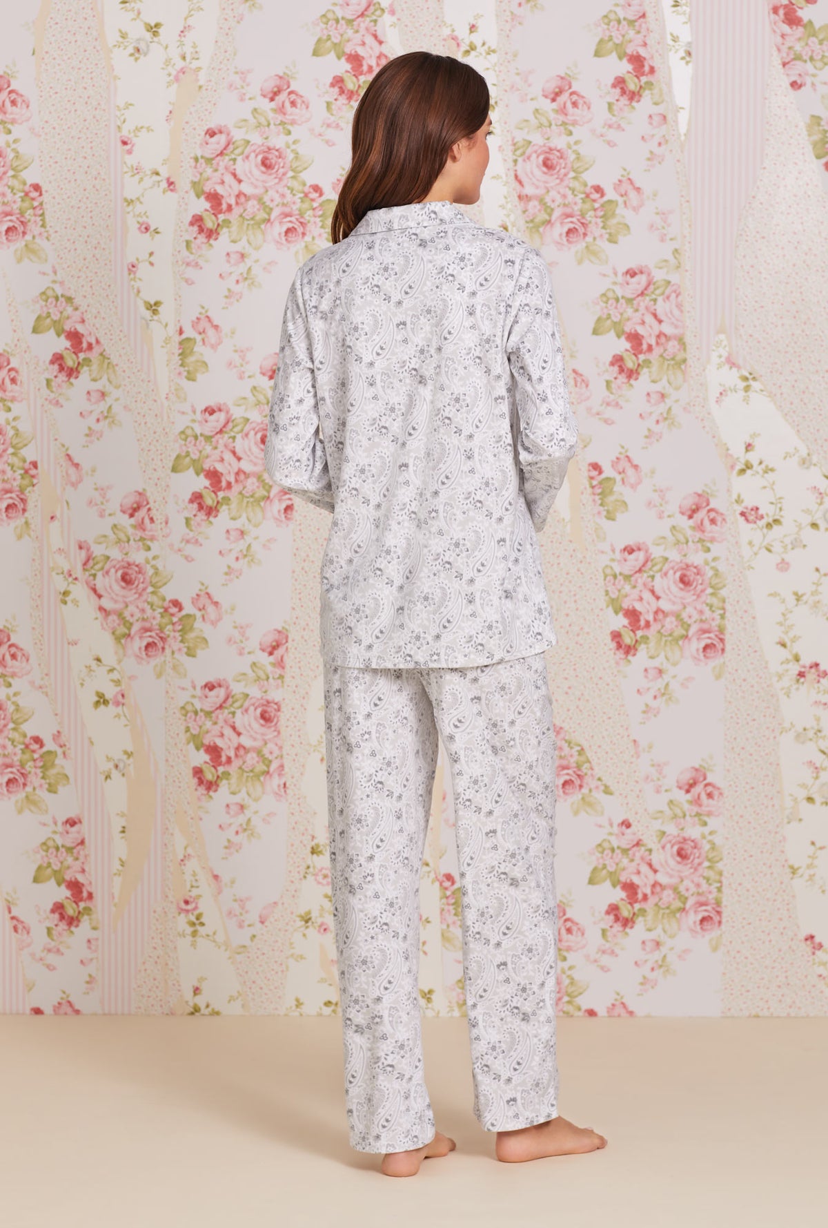 A lady wearing white long sleeve soft fleece pajama with grey paisley print.
