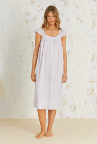 A lady wearing white cap sleeve cotton waltz nightgown with kayla baby rosette print.