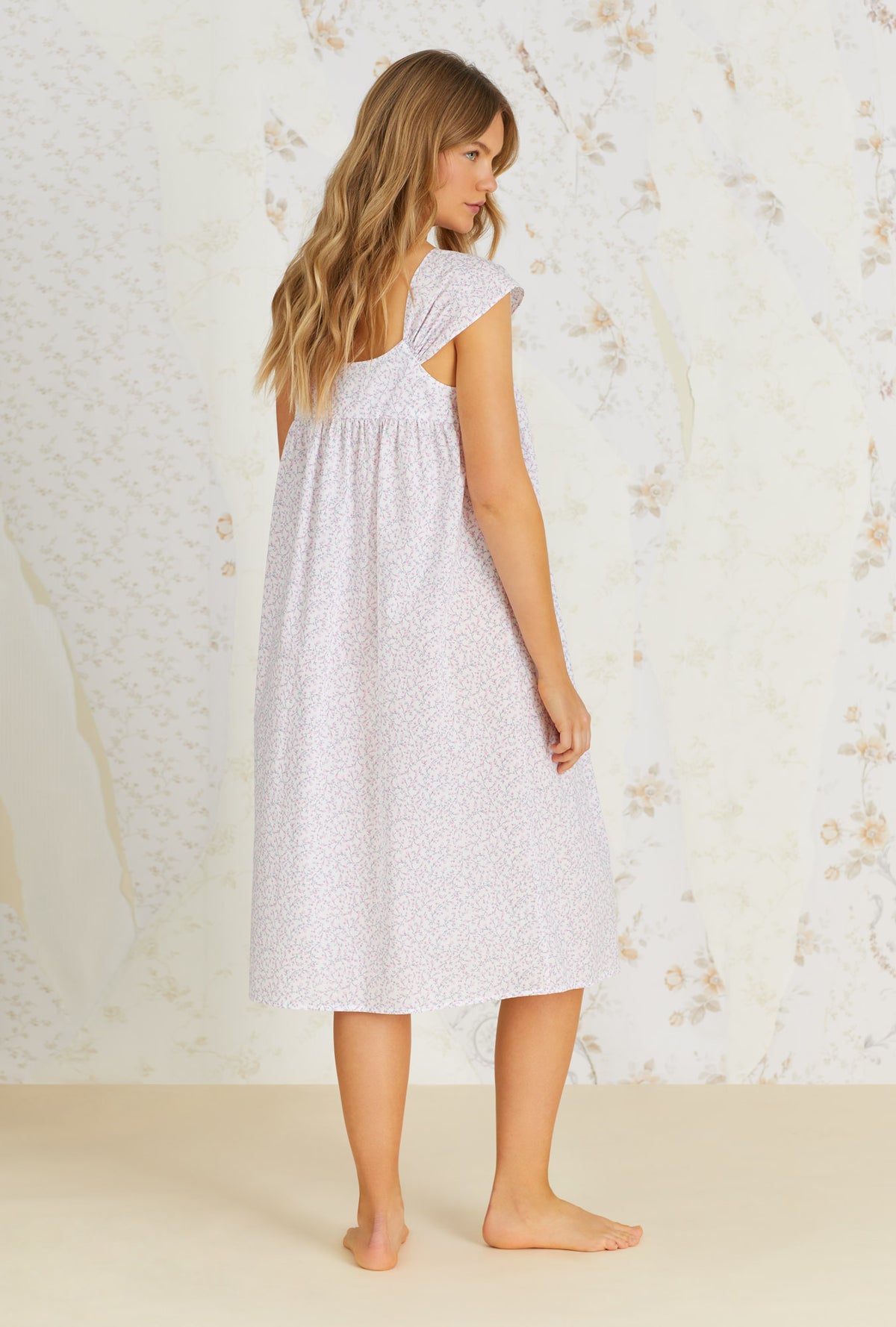 A lady wearing white cap sleeve cotton waltz nightgown with kayla baby rosette print.