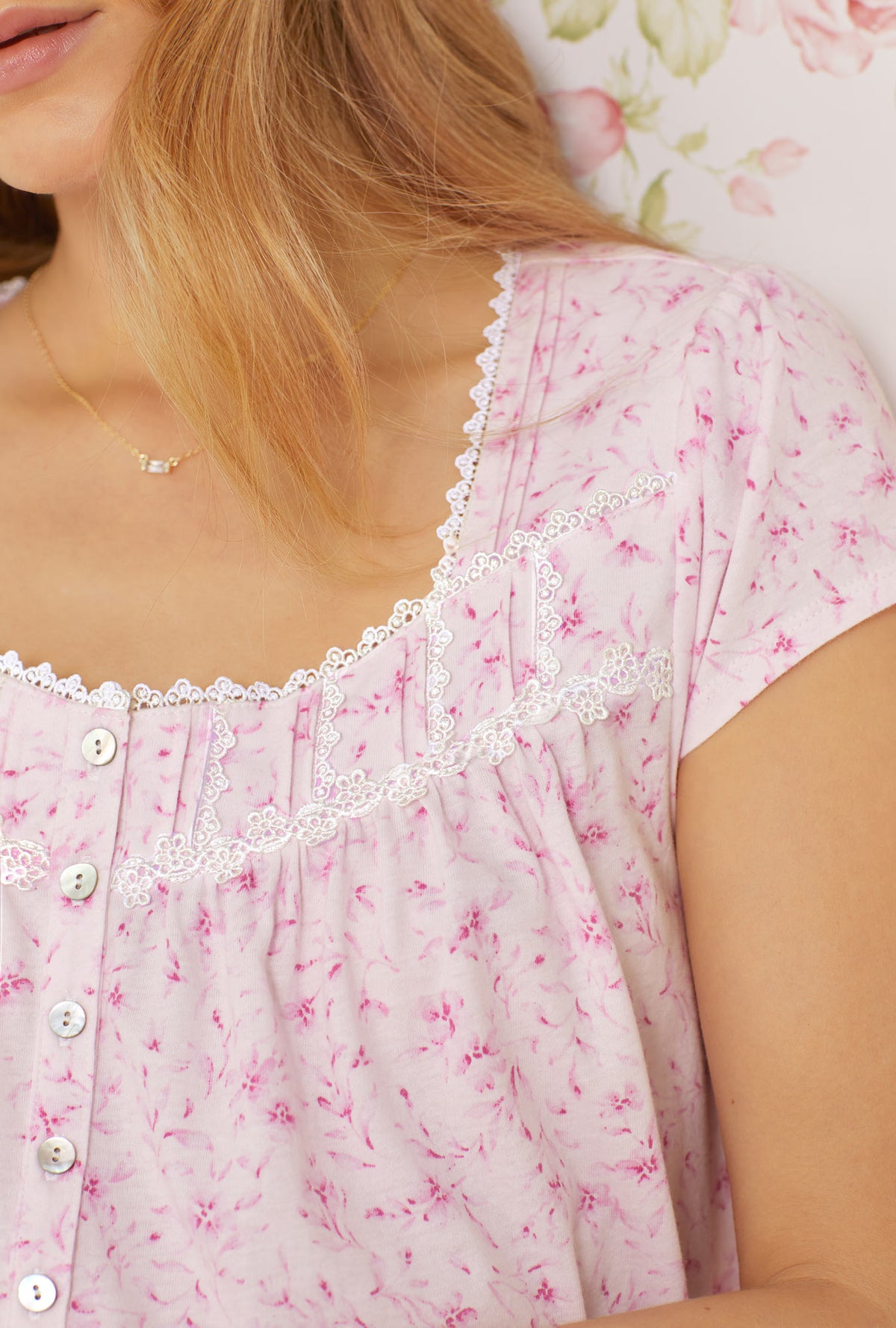 A lady wearing pink cap sleeve short cotton knit nightgown with soft pink floral print.