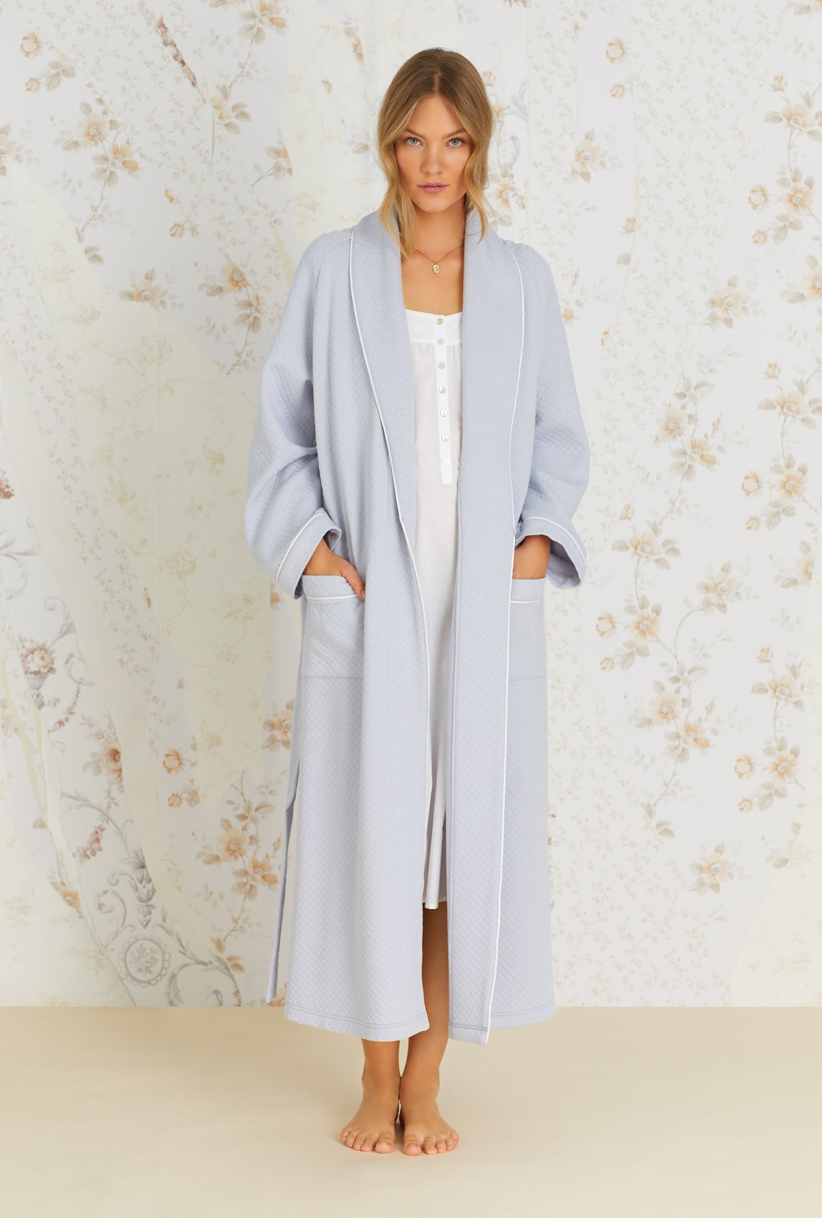 A lady wearing heather grey long sleeve long wrap robe with diamond quilted pattern.