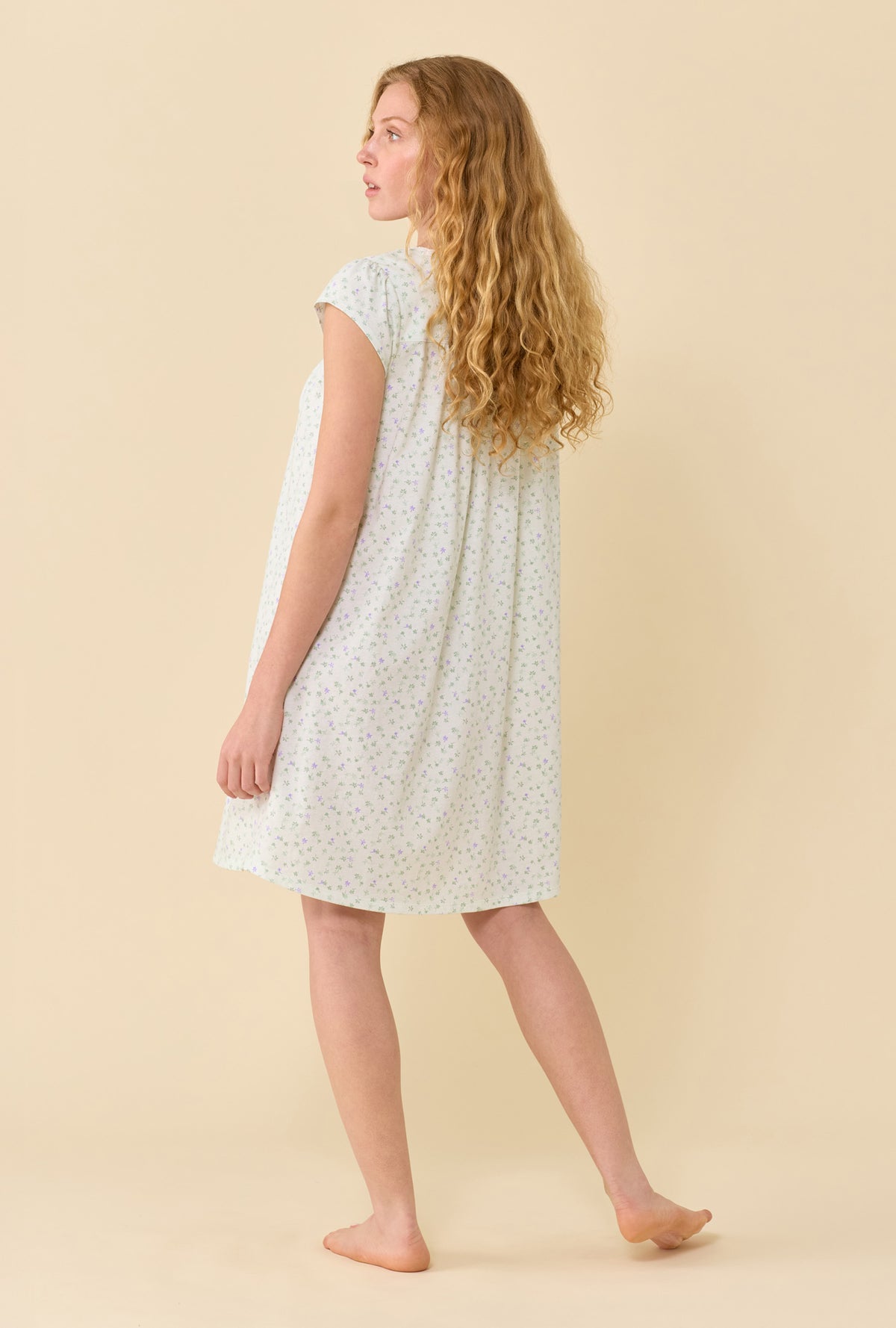 A Lady Wearing Sage Posy Chemise in a back view pose while looking to the side