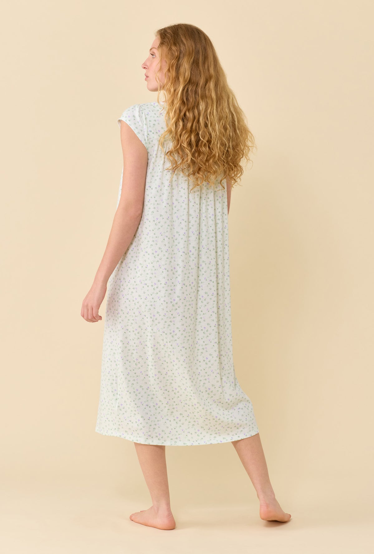 A Lady Wearing Sage Posy Nightgown in a back view pose while looking to the side