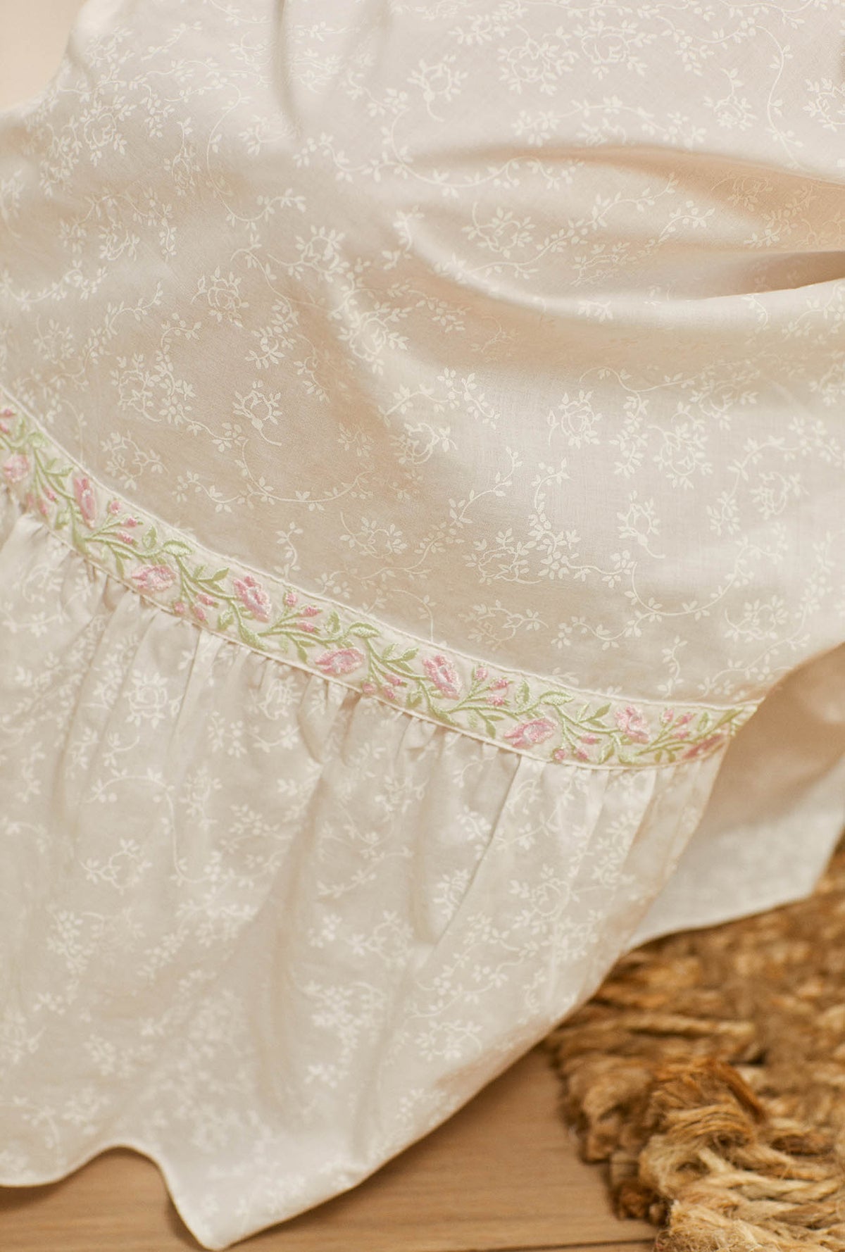 A lady wearing white cap sleeve button front robw with garden rose embroidered pattern.