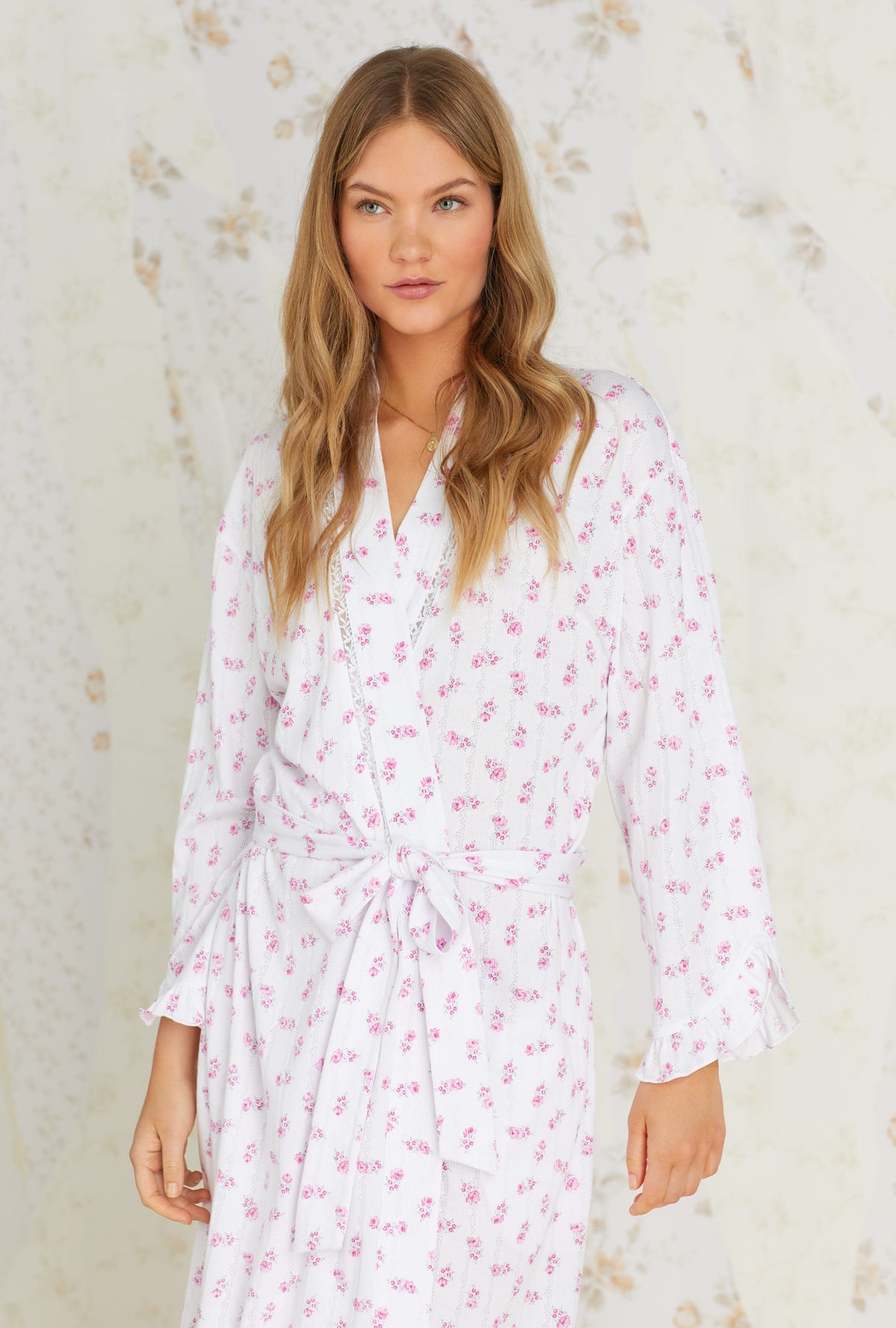 A lady wearing white long sleeve long wrap robe with vintage rose pointelle print.