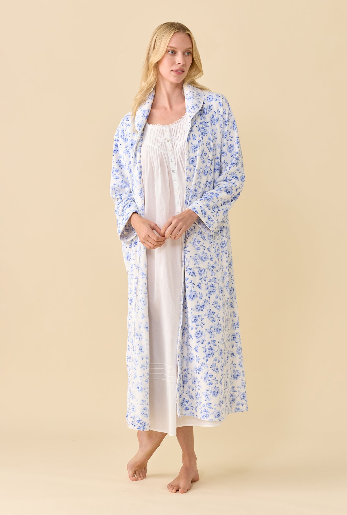 A lady wearing Lux Velour Ballet Zip Robe open over a white nightgown front view in blue floral print with hands together