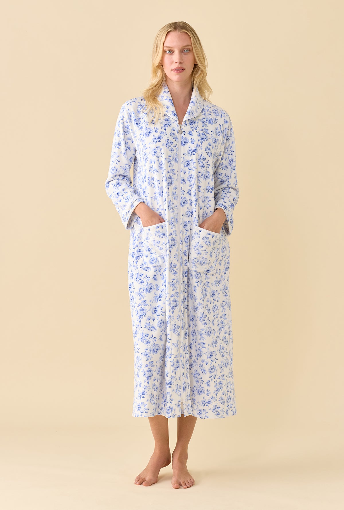 A lady wearing Lux Velour Ballet Zip Robe front view in blue floral print with both hands in patch pockets