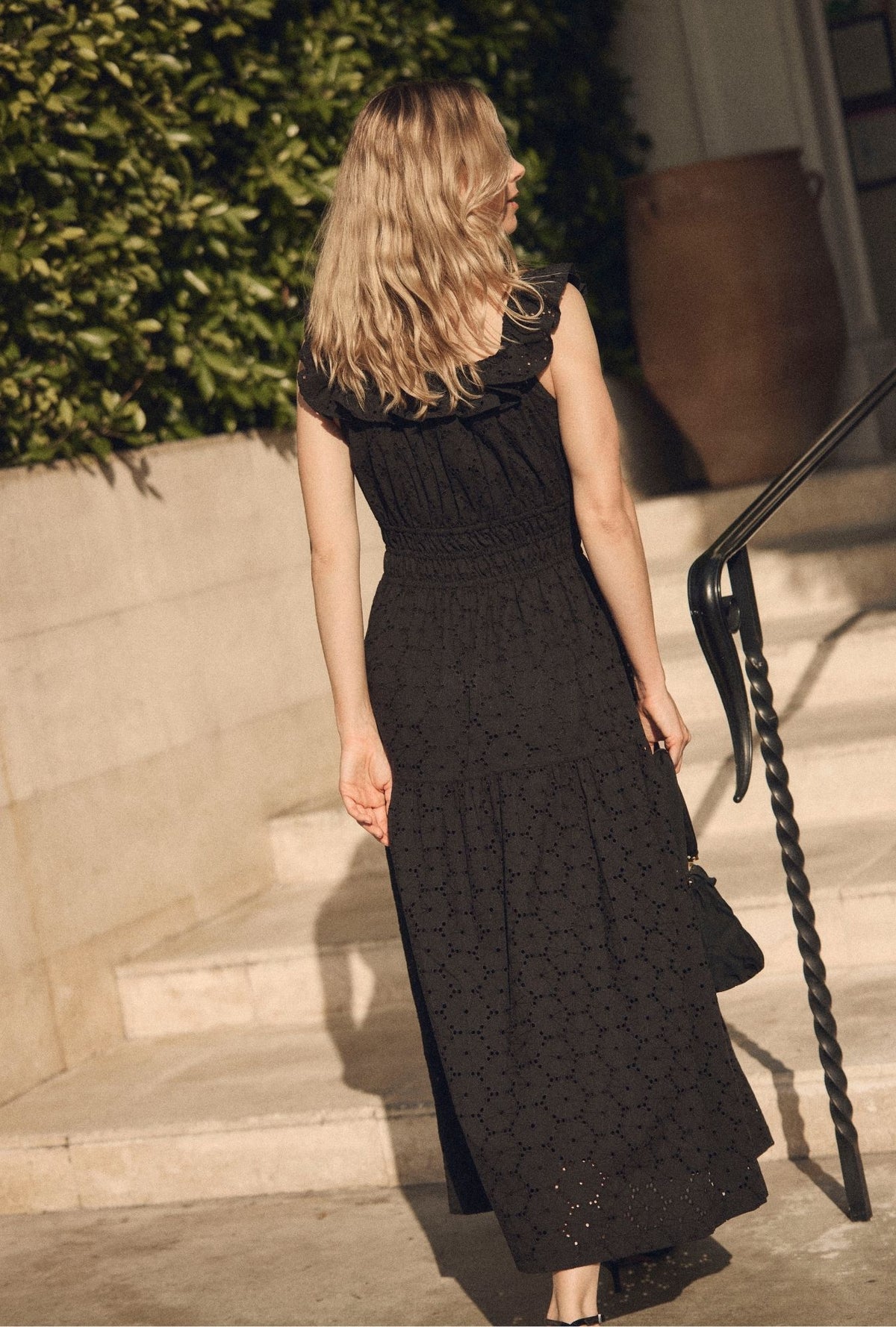 A lady wearing The "Isla" Iconic Black Cotton Maxi Dress back view