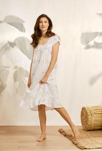 A lady wearing white cap sleeve knit waltz nightgown with butterfly floral print.