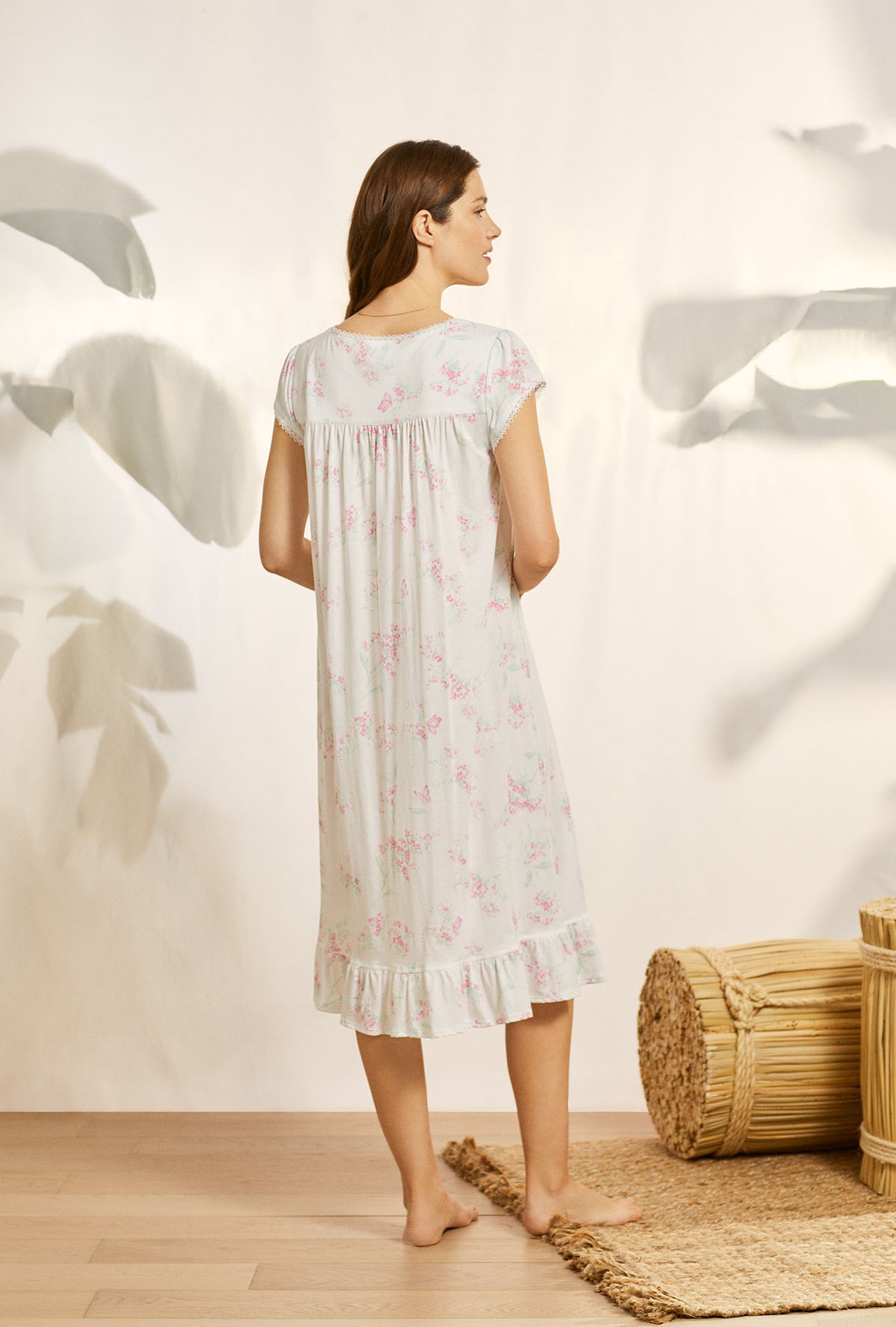 A lady wearing white cap sleeve knit waltz nightgown with butterfly floral print.