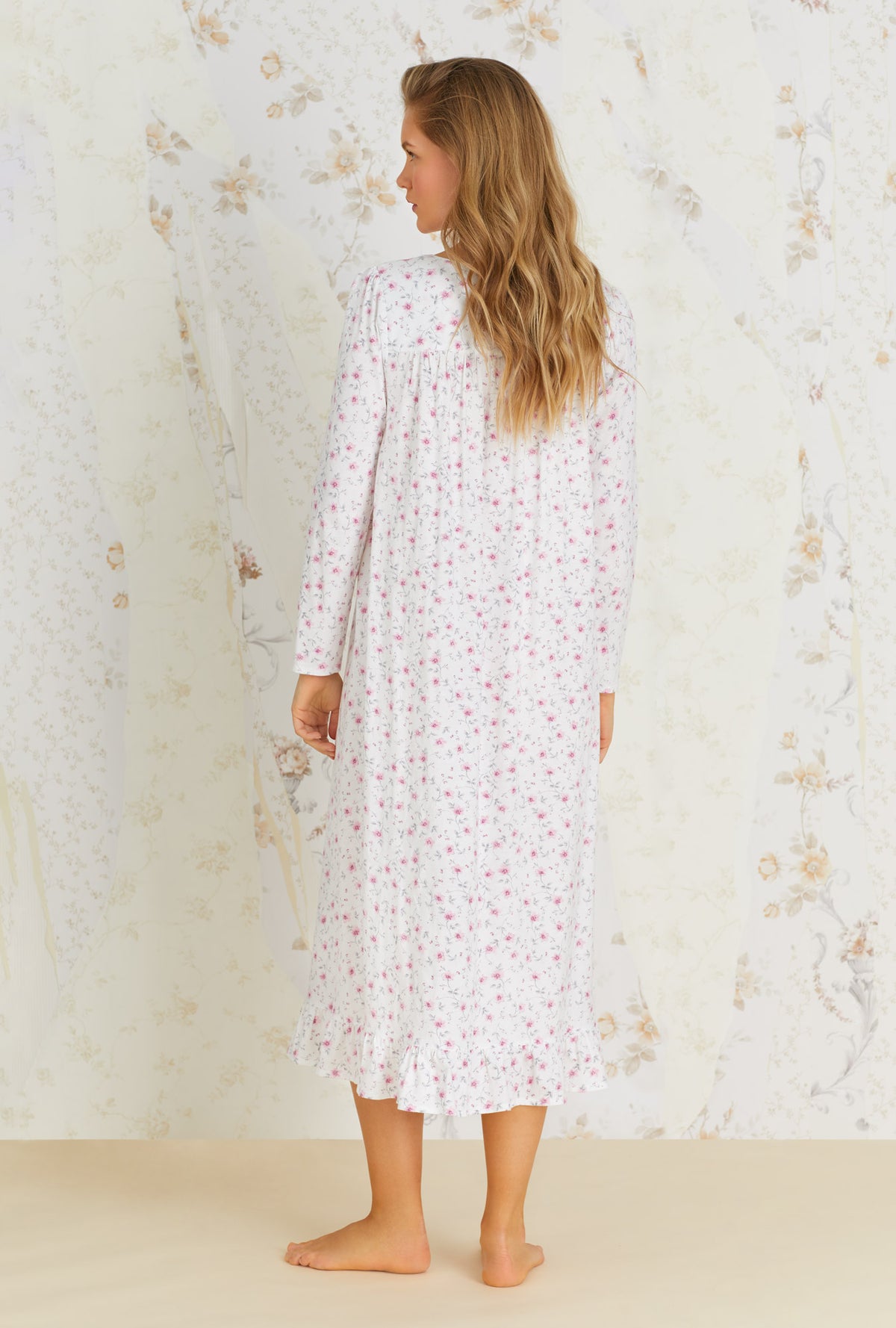 A lady wearing white long sleeve nightgown with trellis bloom print.