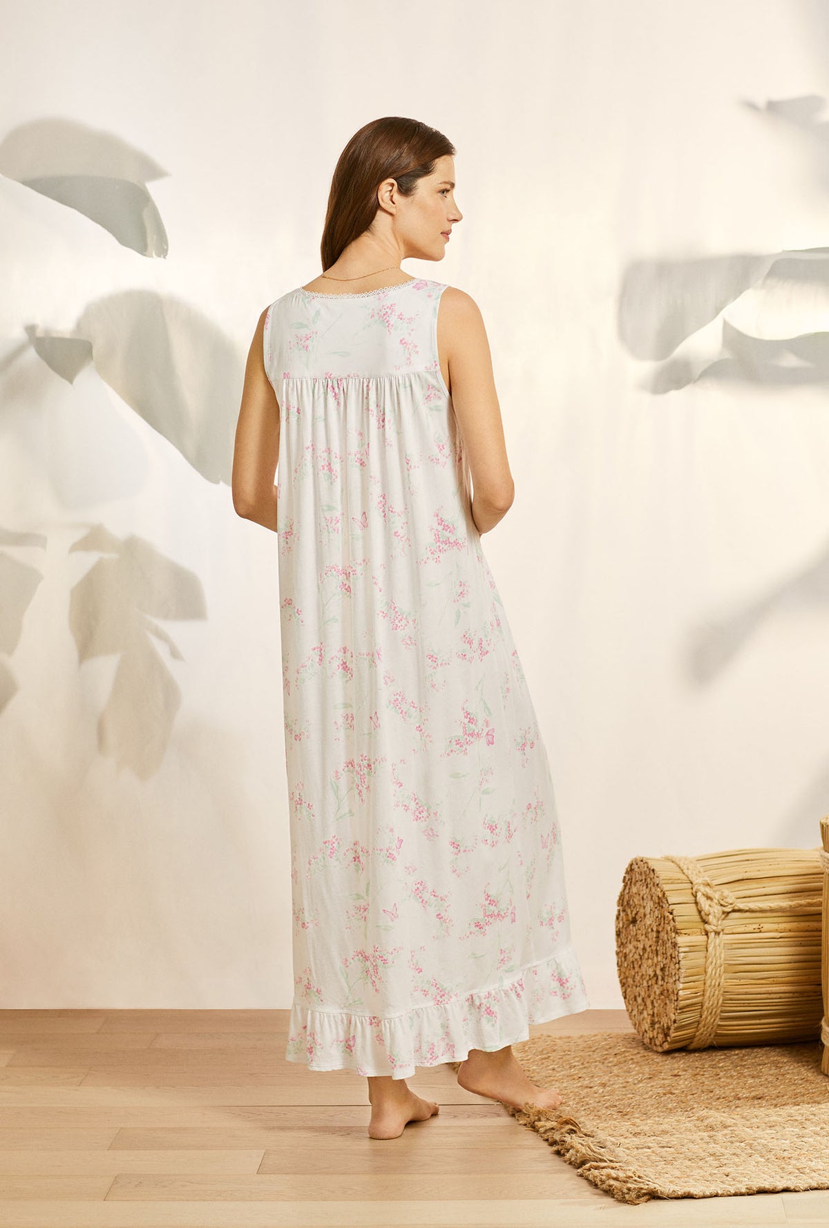 A lady wearing white sleeveless knit eileen nightgown with butterfly floral print.