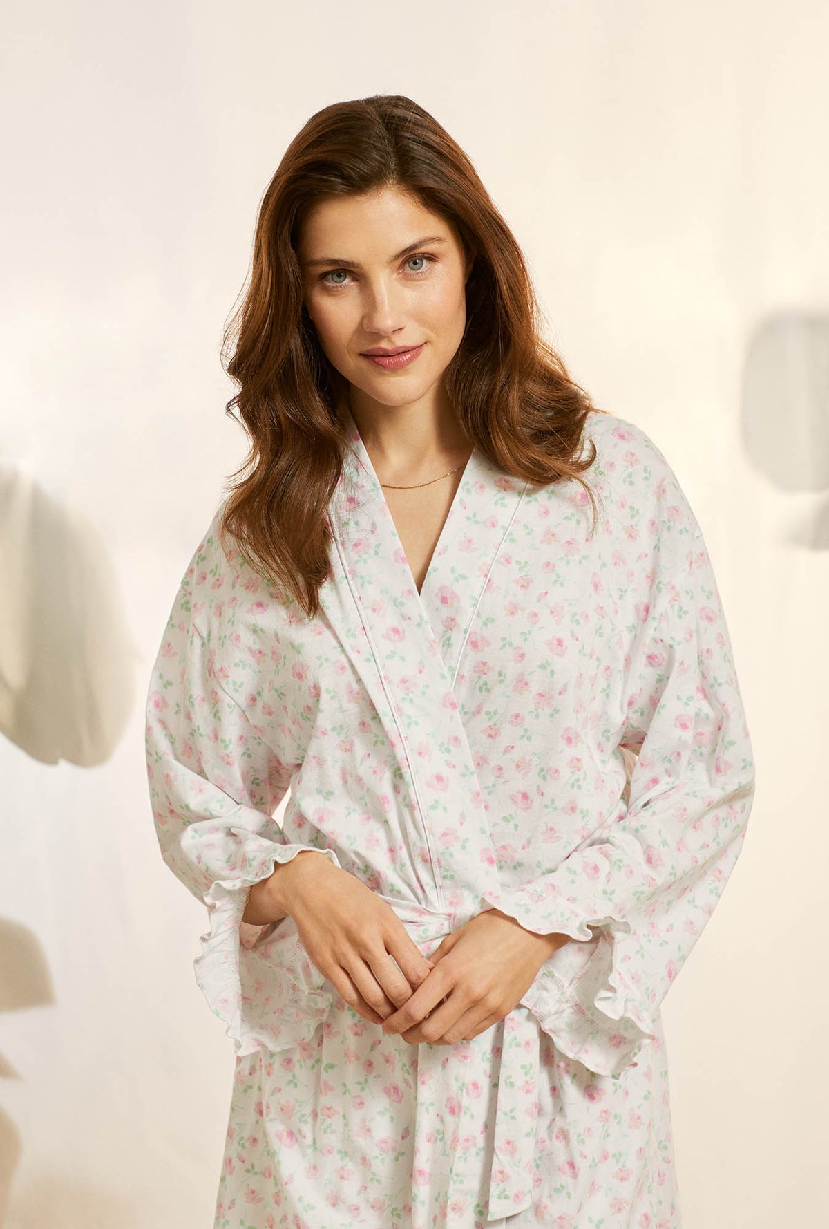 A lady wearing white long sleeve cotton knit short wrap robe with petal dreams.