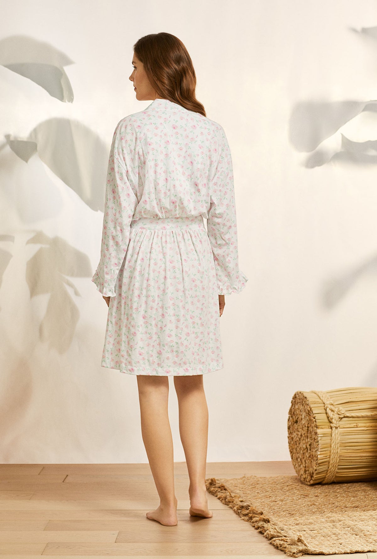 A lady wearing white long sleeve cotton knit short wrap robe with petal dreams.