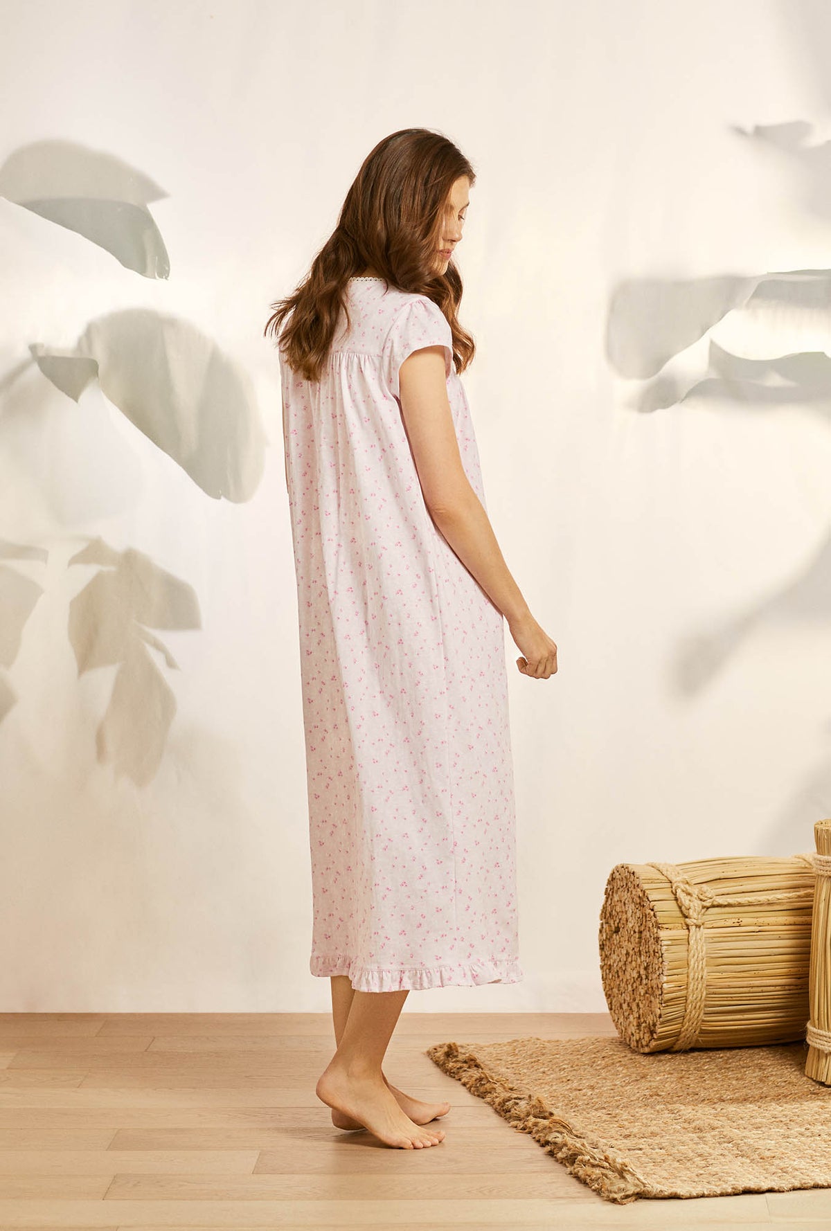 A lady wearing pink cap sleeve cotton knit nightgown with blushing pink floral print.