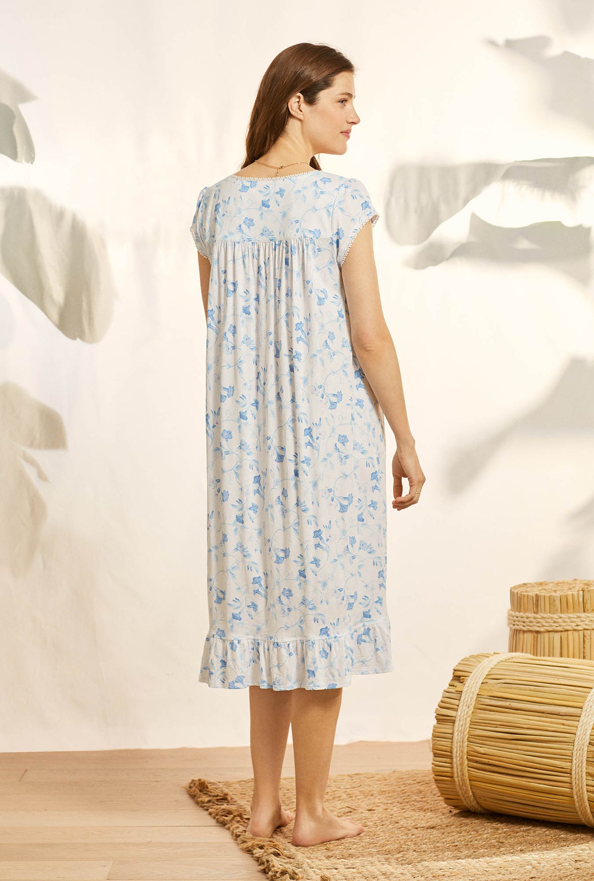 A lady wearing white cap sleeve knit waltz nightgown with morning glory print.