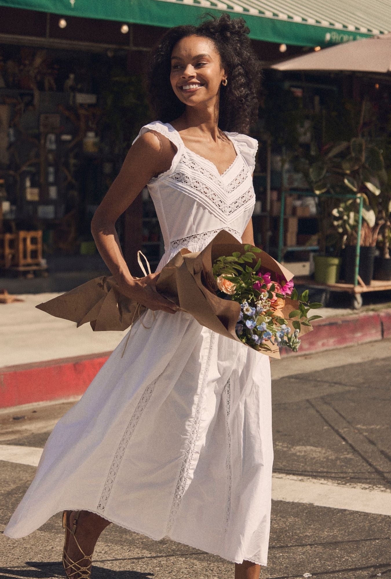 A lady wearing The "Carmela" Soft White Cotton Maxi Dress crossing the road