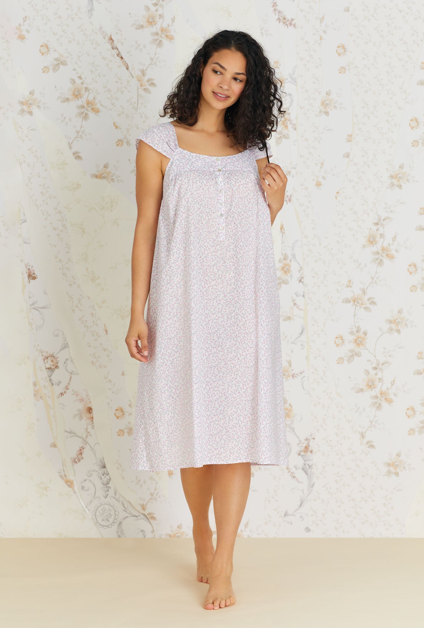 A lady wearing white cap sleeve cotton waltz nightgown with kayla baby rosette print.