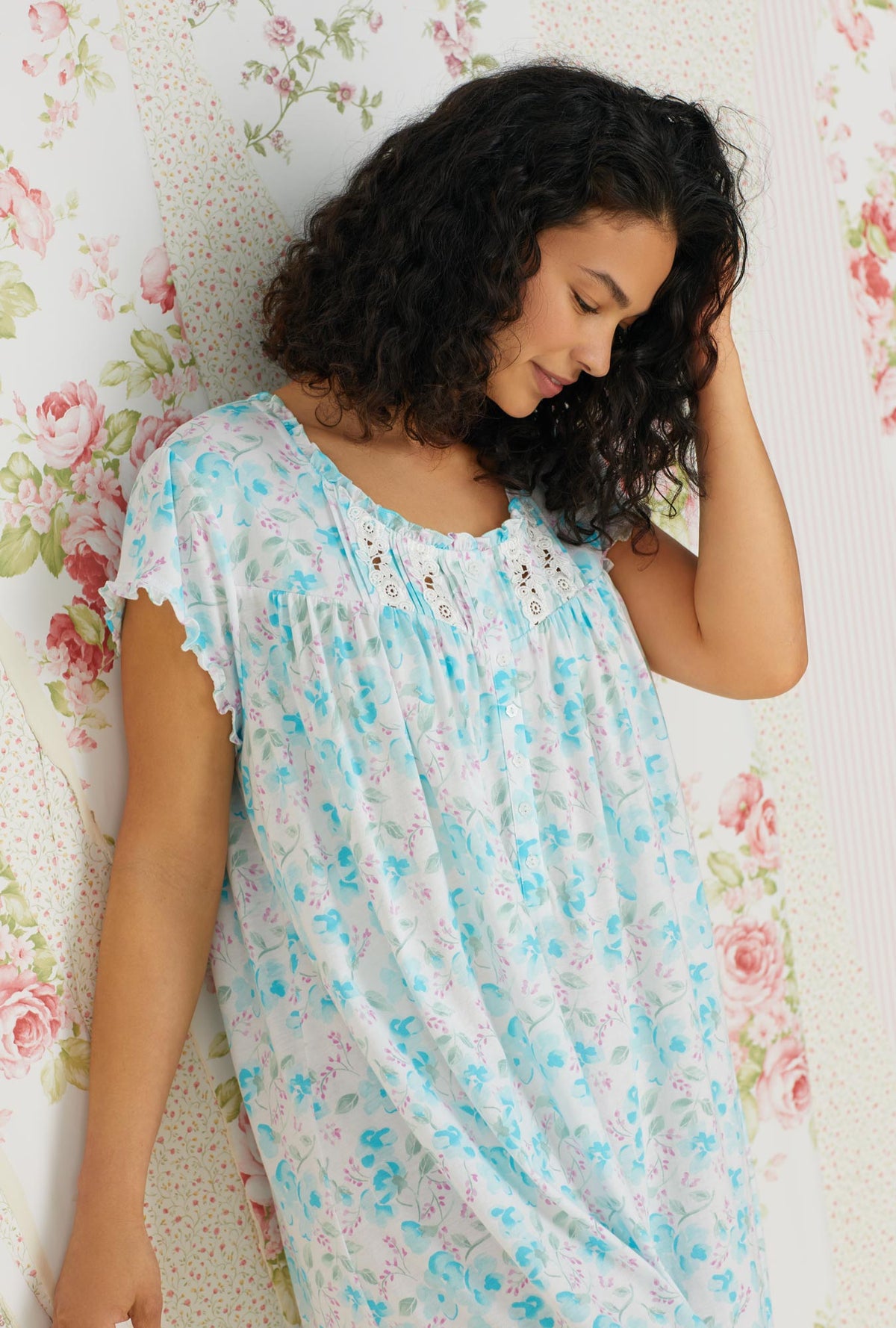 A lady wearing a white and aqua cap sleeve waltz knit nightgown with primrose garden print.